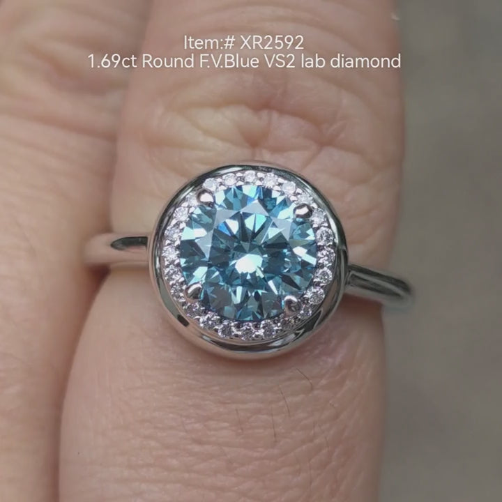 1.69ct round Fancy Vivid Blue lab grown diamond engagement ring with diamond halo in white gold setting, shown on hand in natural light