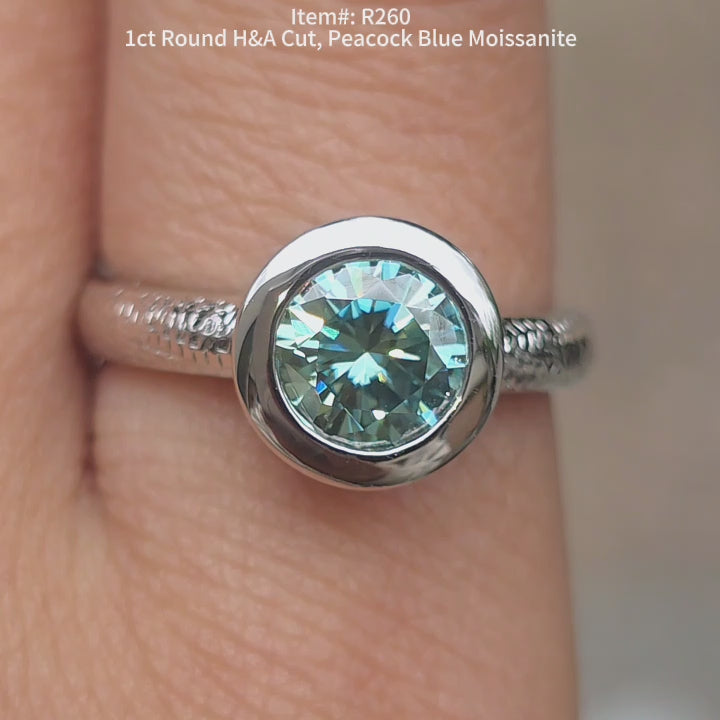 DovEggs 1ct Round Hearts & Arrows cut peacock blue moissanite ring sparkling in natural lighting video.