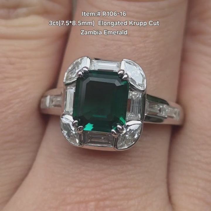 3ct elongated Krupp cut Zambia emerald engagement ring with diamond halo of marquise and baguette accents, shown on hand in natural light