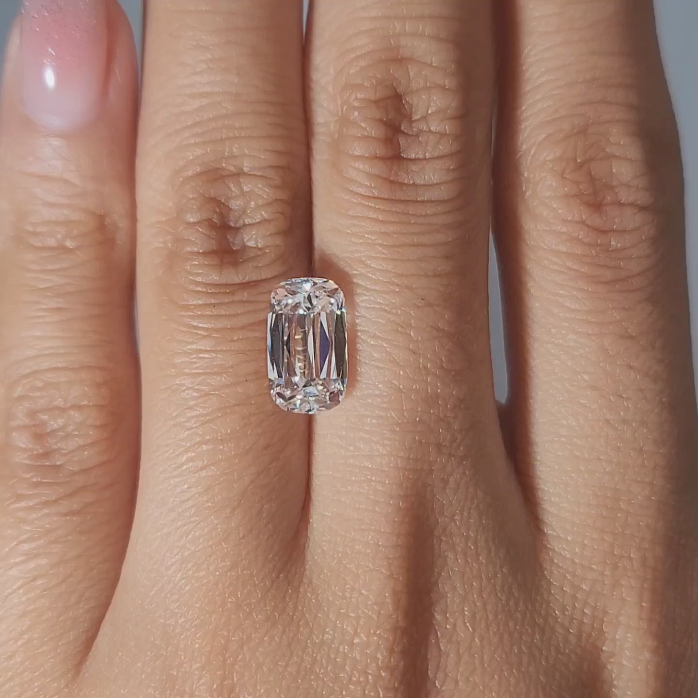Close-up video of 3.12ct cushion cut diamond in warm light, emphasizing chunky faceting