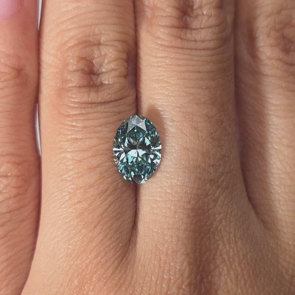 Hand modeling a 2.05ct oval cut fancy vivid blue VS1 lab diamond in warm indoor light.