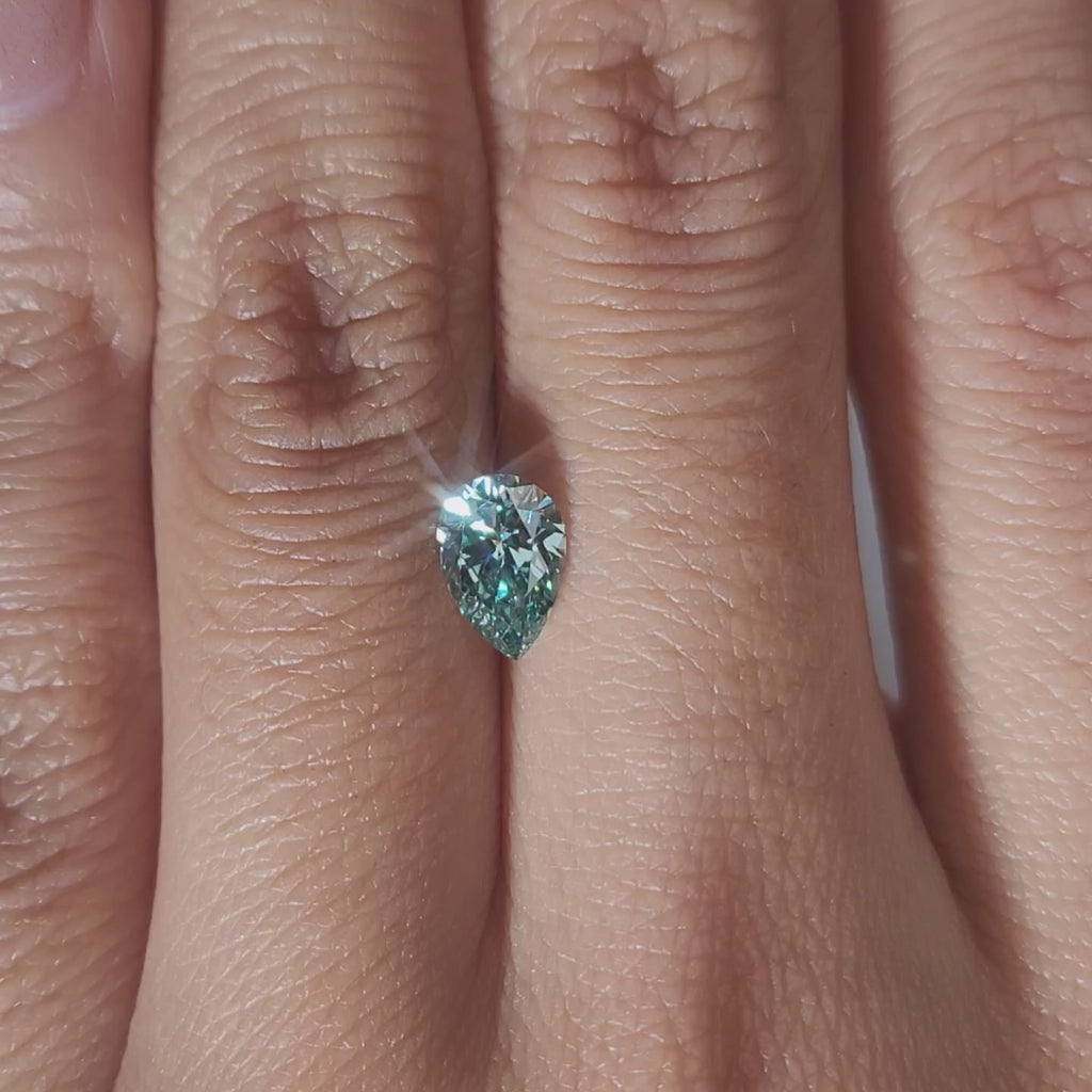 "Hand-modeled video of 0.840ct green pear diamond in warm indoor lighting"