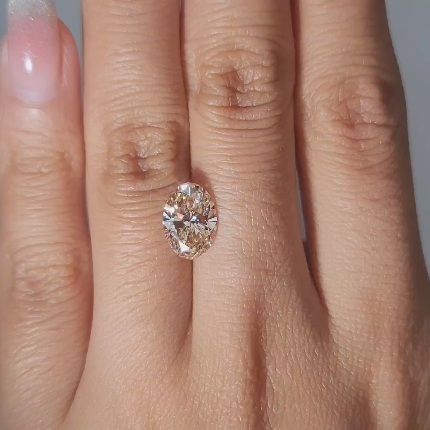 2.36ct Oval orange diamond shimmering in warm handheld lighting