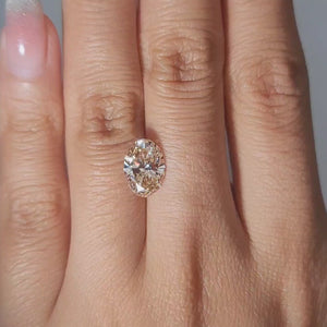 2.36ct Oval orange diamond shimmering in warm handheld lighting