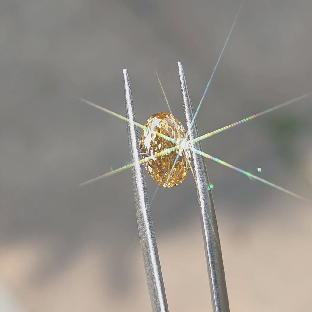 2.22ct oval brilliant cut fancy vivid yellow VVS1 lab diamond sparkling under outdoor sunlight.