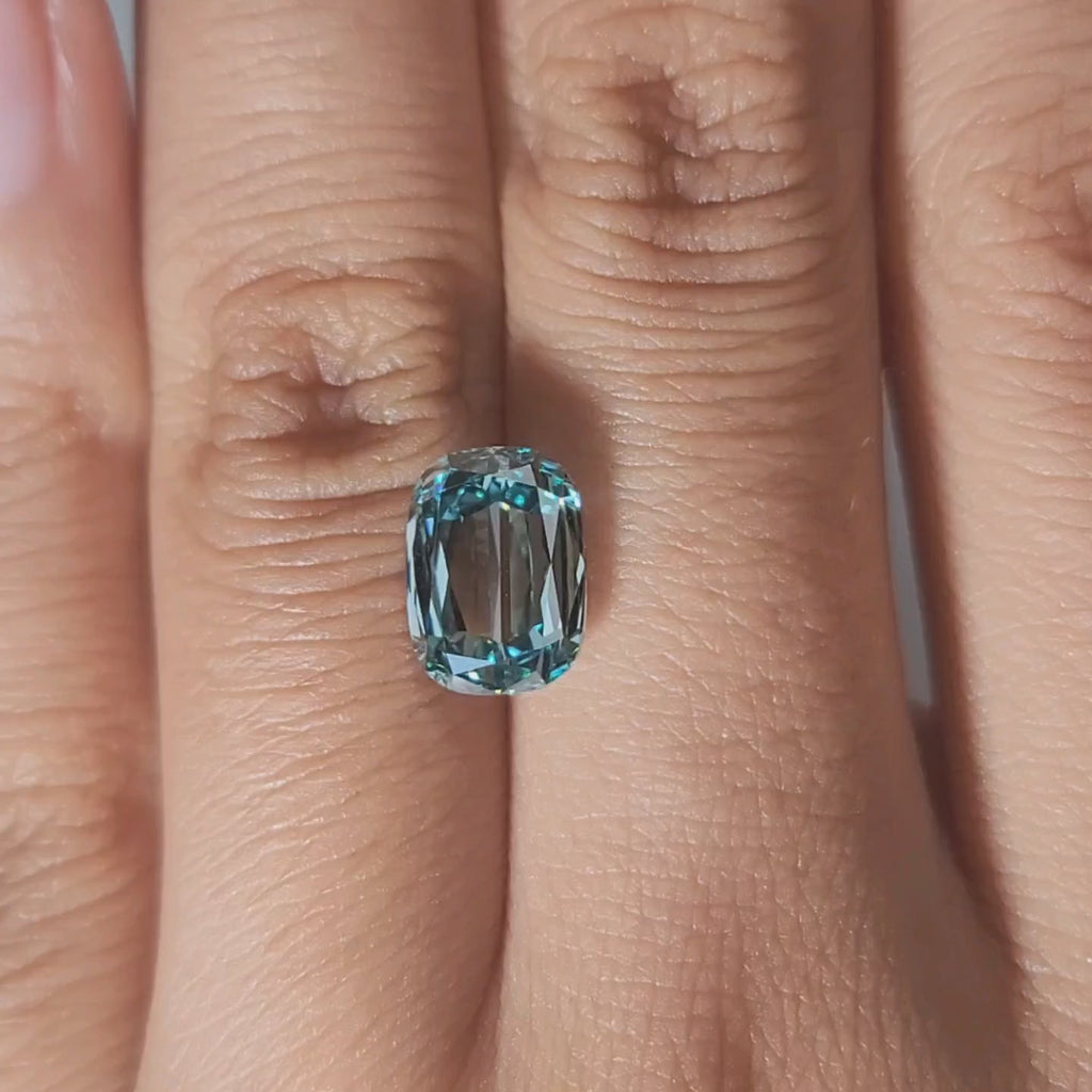 Close-up hand video of 3.002ct blue cushion diamond in warm lighting