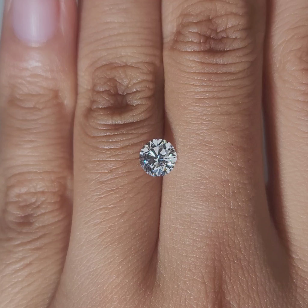 Hand-modeled close-up of 0.696ct round diamond under warm indoor lighting
