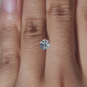 Hand-modeled close-up of 0.696ct round diamond under warm indoor lighting