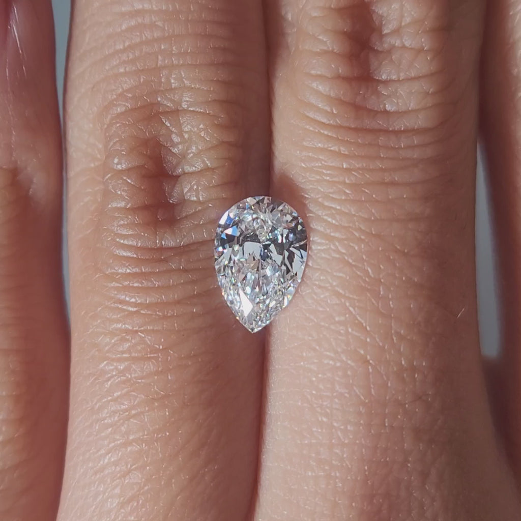 "Hand-modeled video of 1.239ct pear diamond in warm indoor lighting"