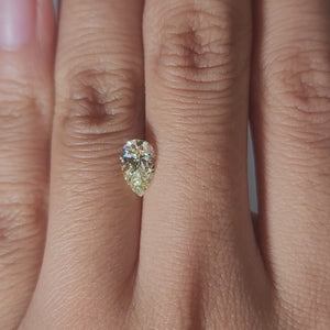 Close-up video of 0.92ct fancy yellow pear cut diamond under warm light