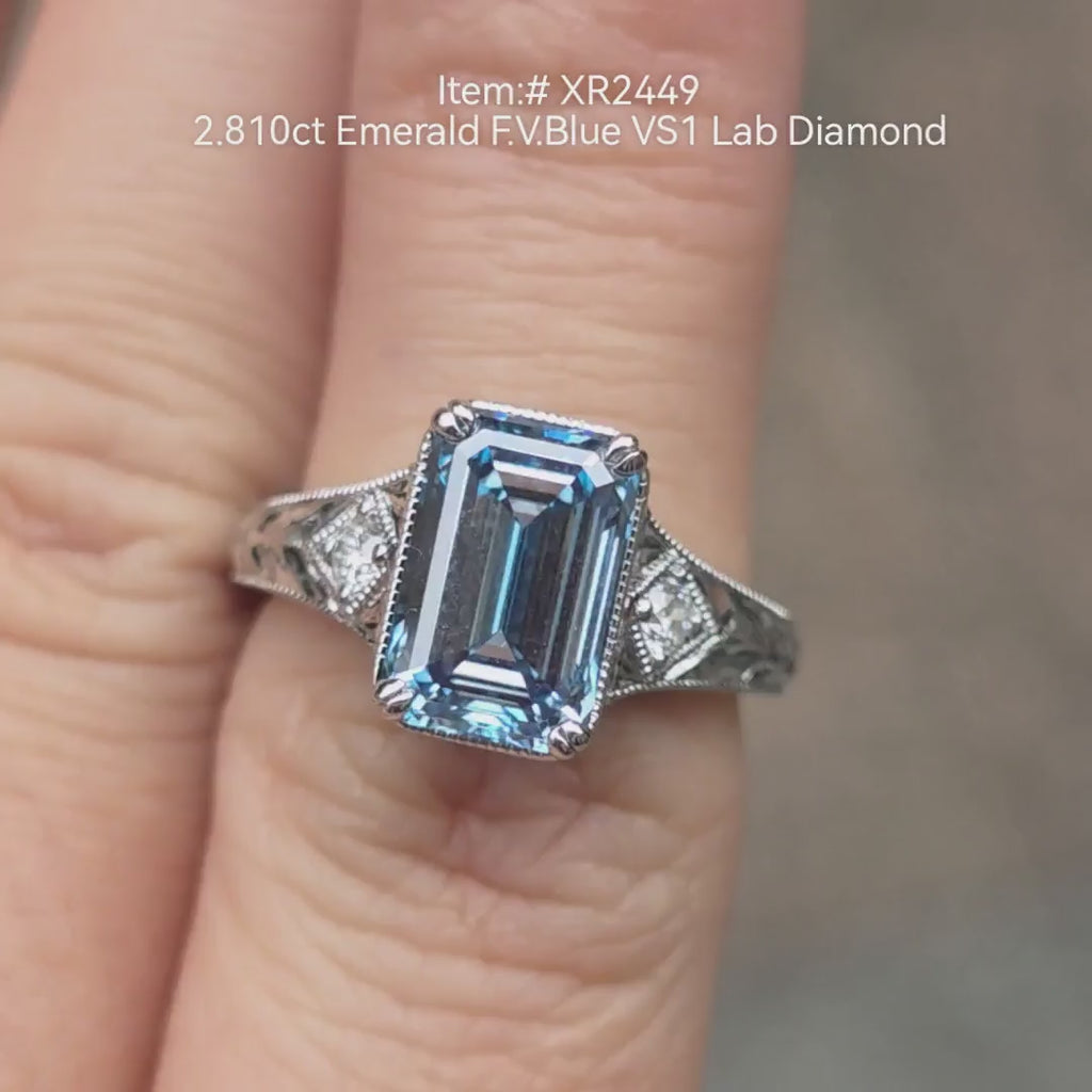 2.81ct emerald cut Fancy Vivid Blue lab grown diamond engagement ring with tapered baguette side stones, shown on hand in natural light 