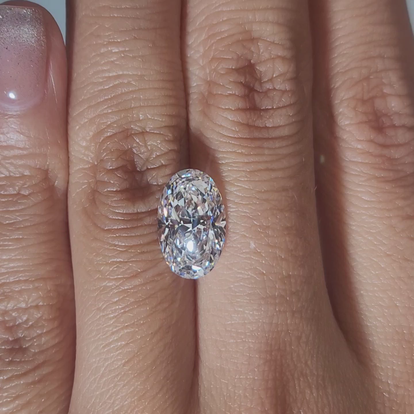 "Hand-modeled video of 3.348ct oval diamond in warm indoor lighting"
