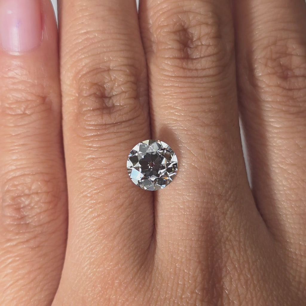 Hand modeling a 2.10ct round European cut E color VVS1 lab diamond in warm indoor light.