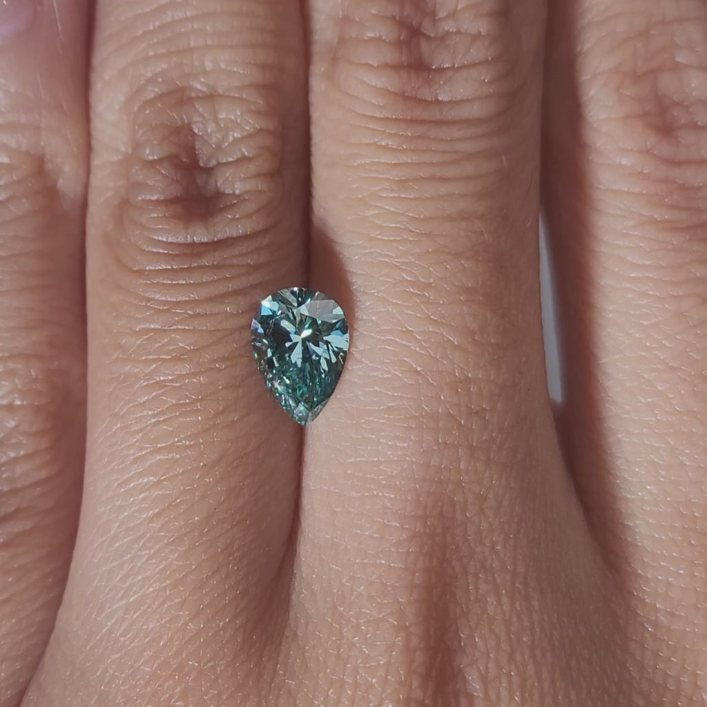 "Hand-modeled video of 1.186ct green pear diamond in warm indoor lighting"