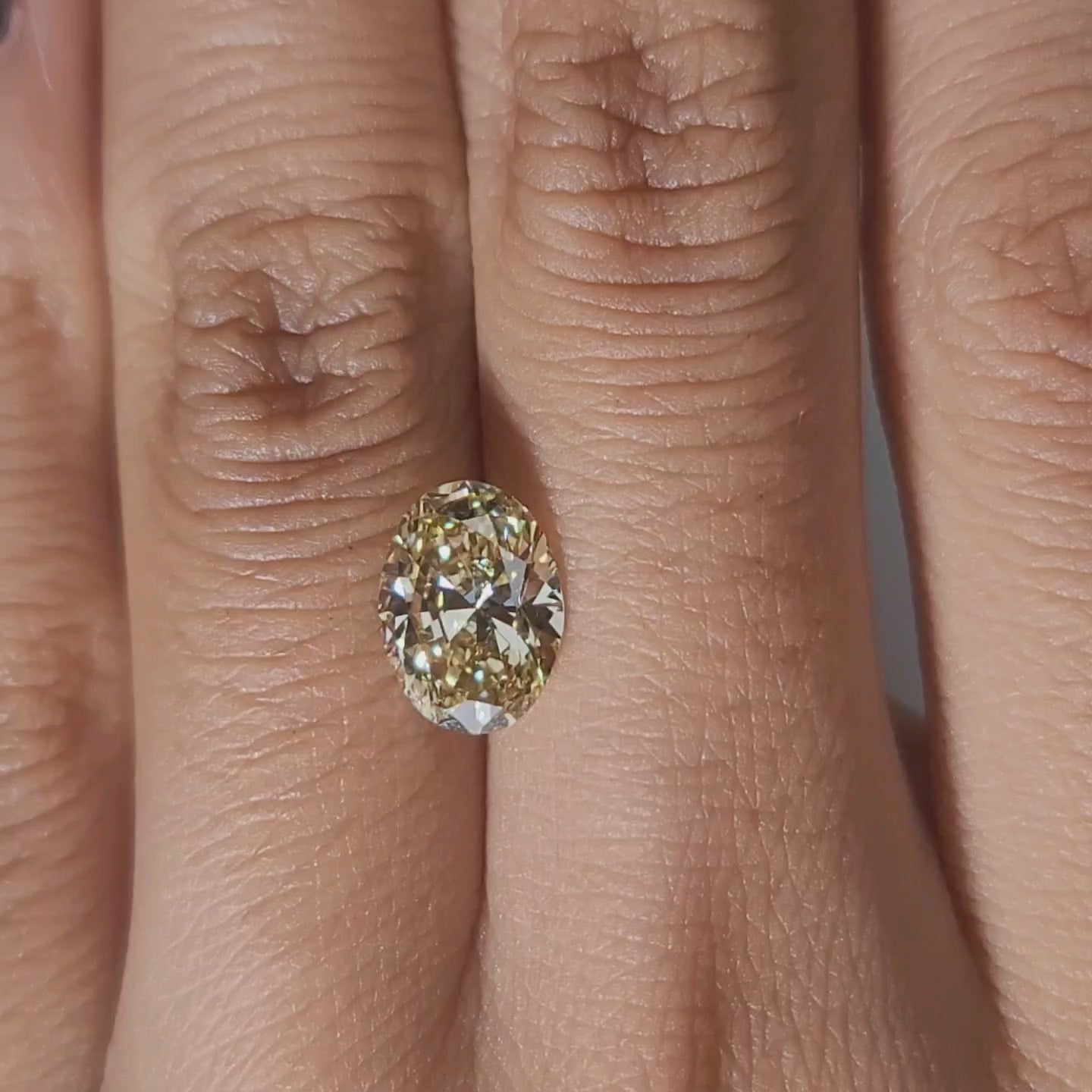 Hand-worn video of 2.005ct yellow oval diamond in warm interior lighting