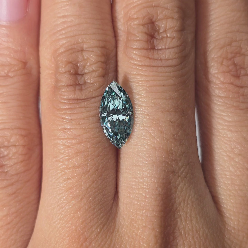 A hand presents a 2.08ct marquise cut fancy vivid blue lab diamond in warm light.