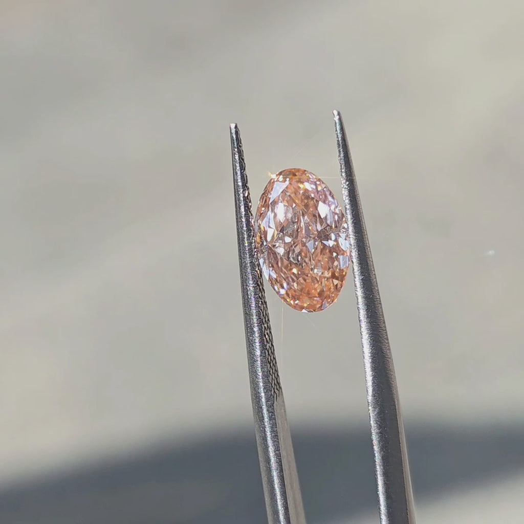2.29ct oval brilliant cut fancy vivid pink VS1 lab diamond displaying vibrant pink saturation in outdoor sunlight.