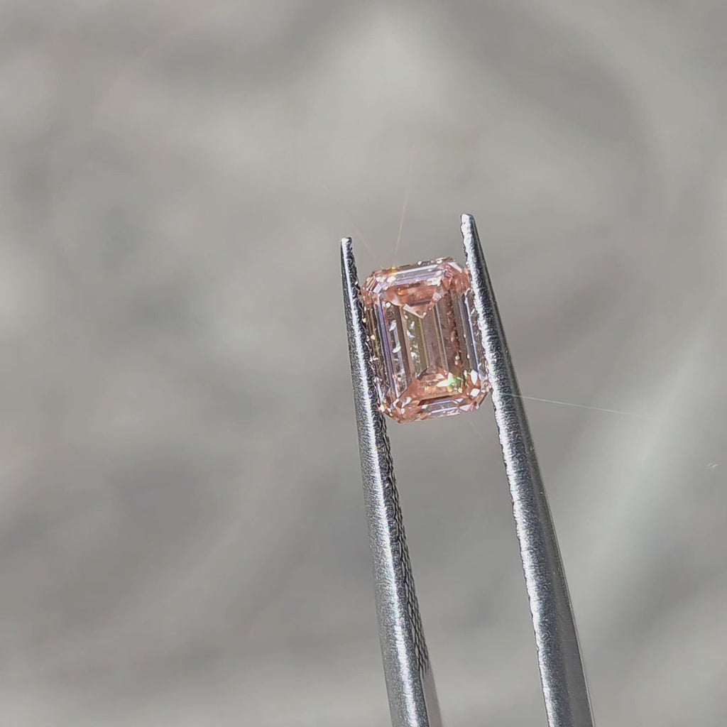 1.05ct emerald cut fancy vivid pink VS1 lab diamond showing vibrant pink in step-cut pattern in outdoor sunlight.