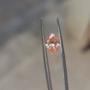 2.10ct Oval lab diamond glowing with vivid pink hues under natural sunlight