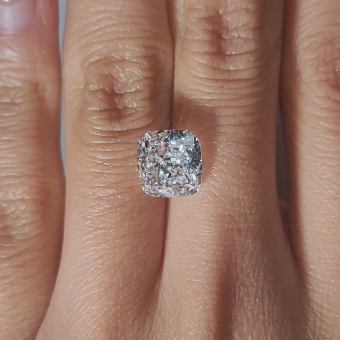 "Hand-modeled video of 3.73ct cushion diamond in warm indoor lighting"
