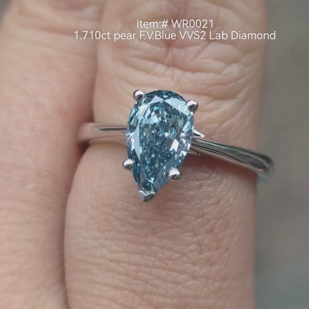 1.71ct pear-cut Fancy Vivid Blue lab grown diamond engagement ring shown on hand in natural light, six-prong solitaire setting 