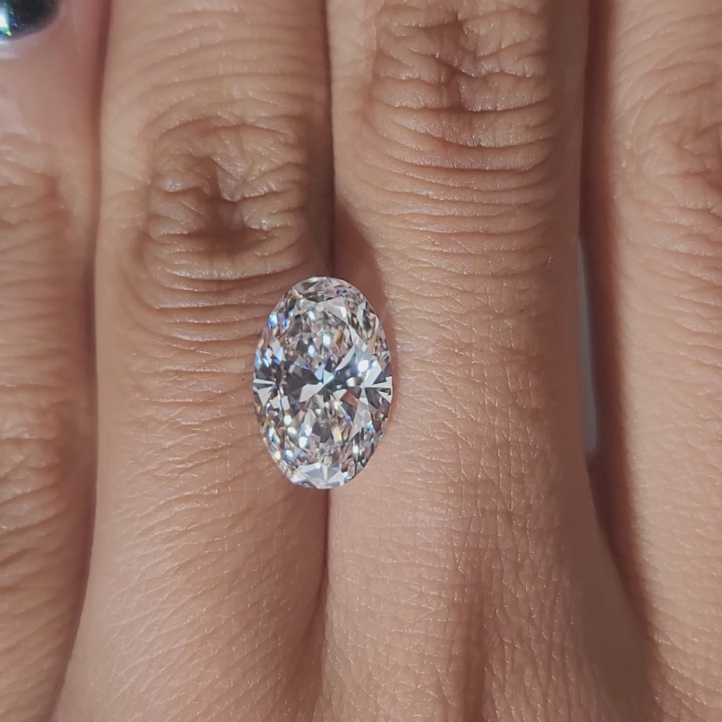 Hand-modeled video of 3.562ct oval E color diamond in warm indoor lighting