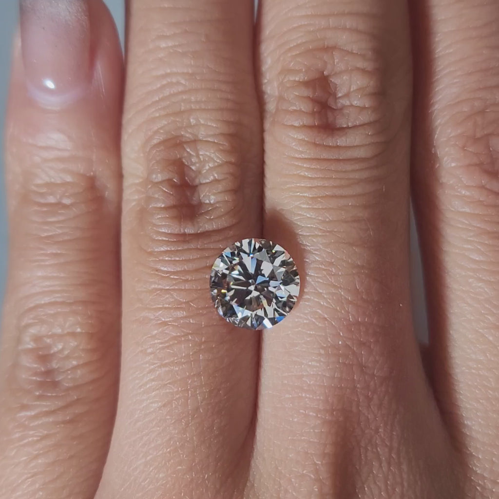 "Hand-modeled video of 2.667ct round diamond in warm indoor lighting"