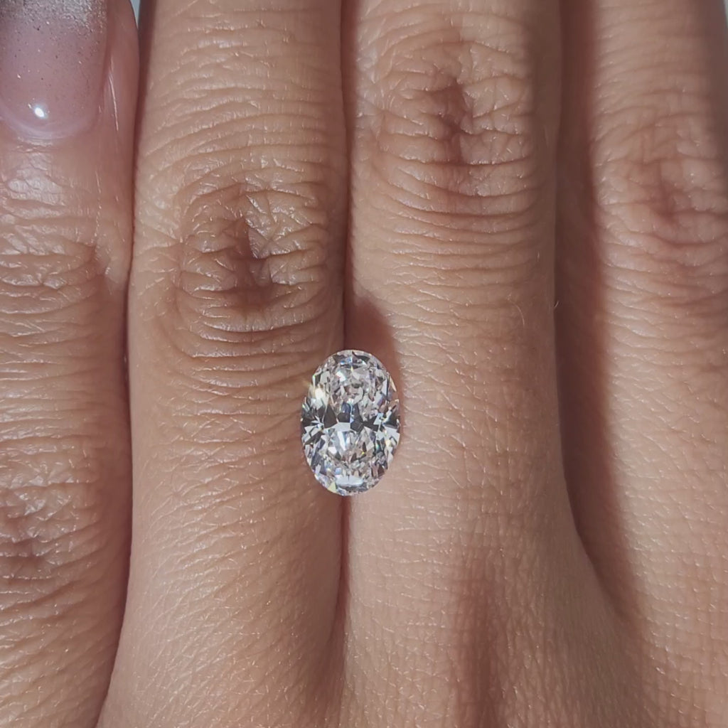 "Hand-modeled video of 1.651ct oval diamond in warm indoor lighting"