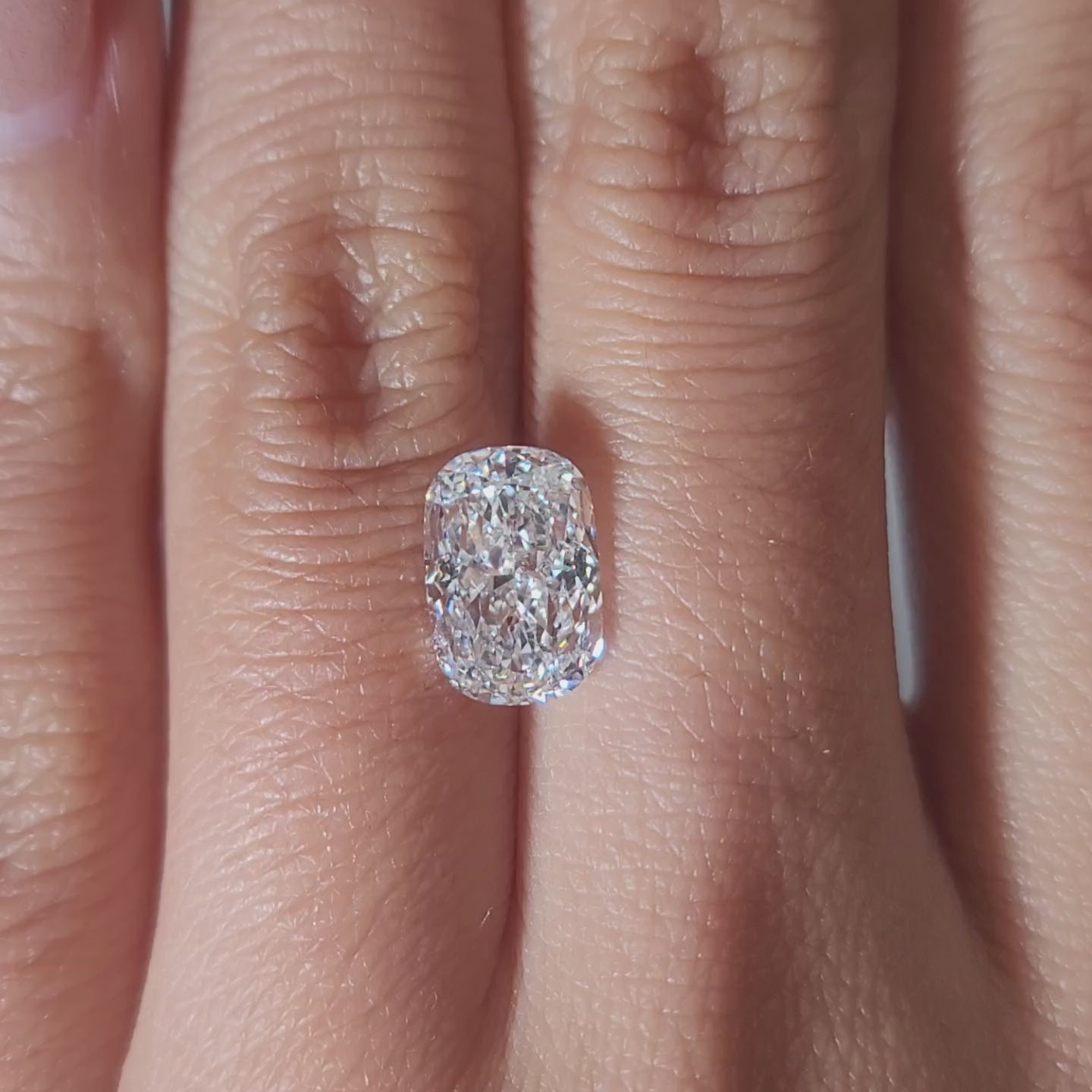 "Hand-modeled video of 2.117ct cushion diamond in warm indoor lighting"