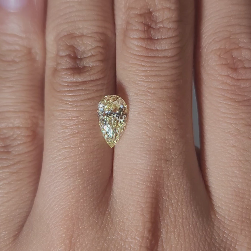 Hand-modeled video of 1.67ct vivid yellow pear diamond under warm light