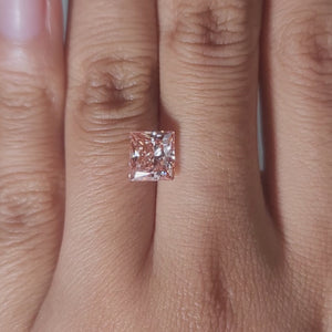 Close-up video of 2.01ct vivid pink princess cut diamond under warm light