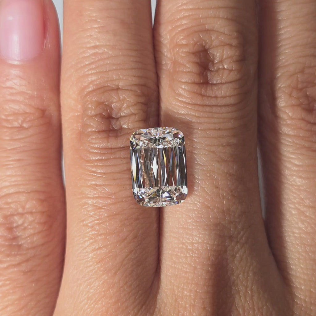 Hand modeling a 5.07ct elongated cushion brilliant cut lab diamond in warm light.