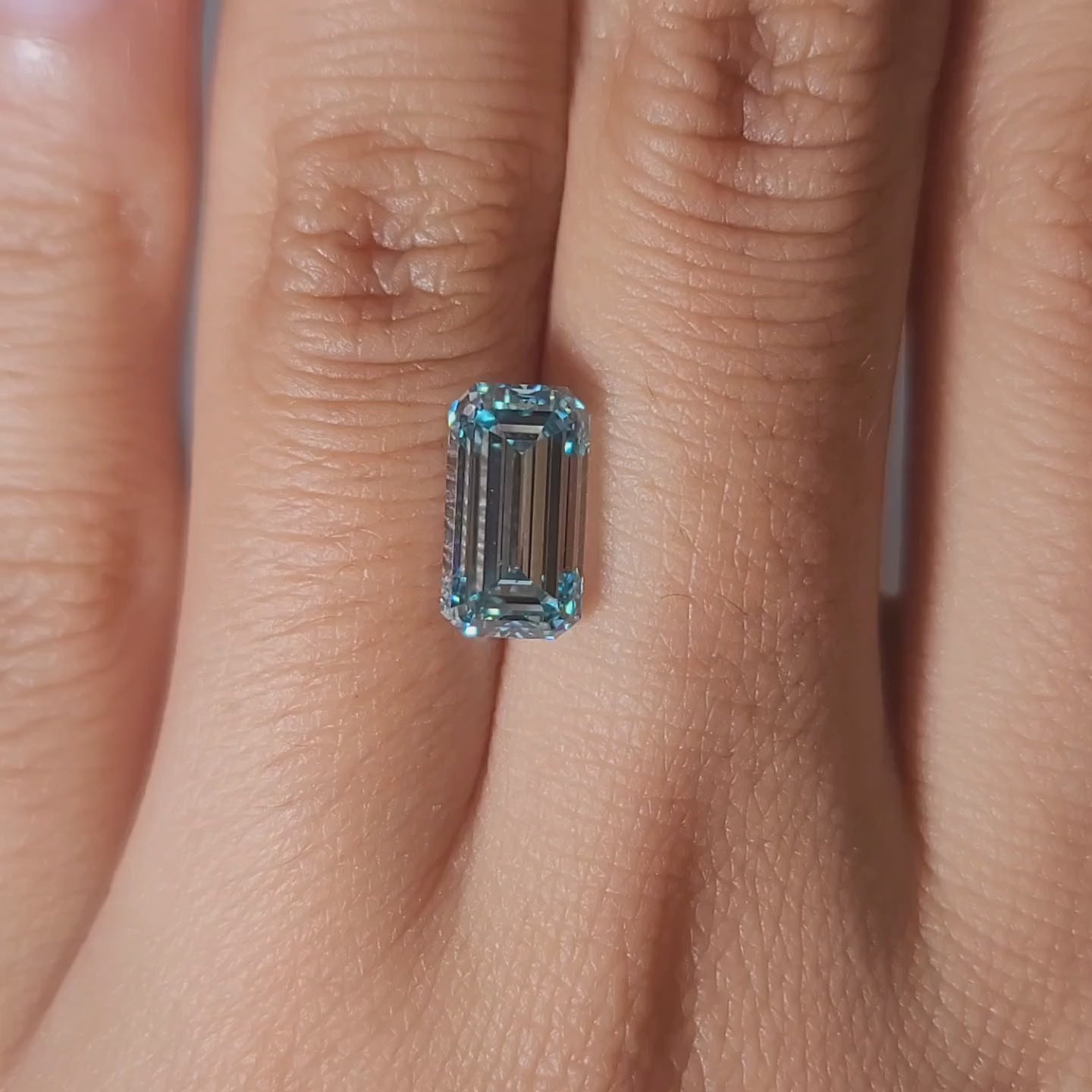 "Hand-worn video showcasing 3.03ct bluish green emerald cut in gallery lighting"