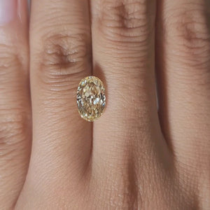 Finger-modeled video of 2.27ct yellow oval diamond under warm lighting