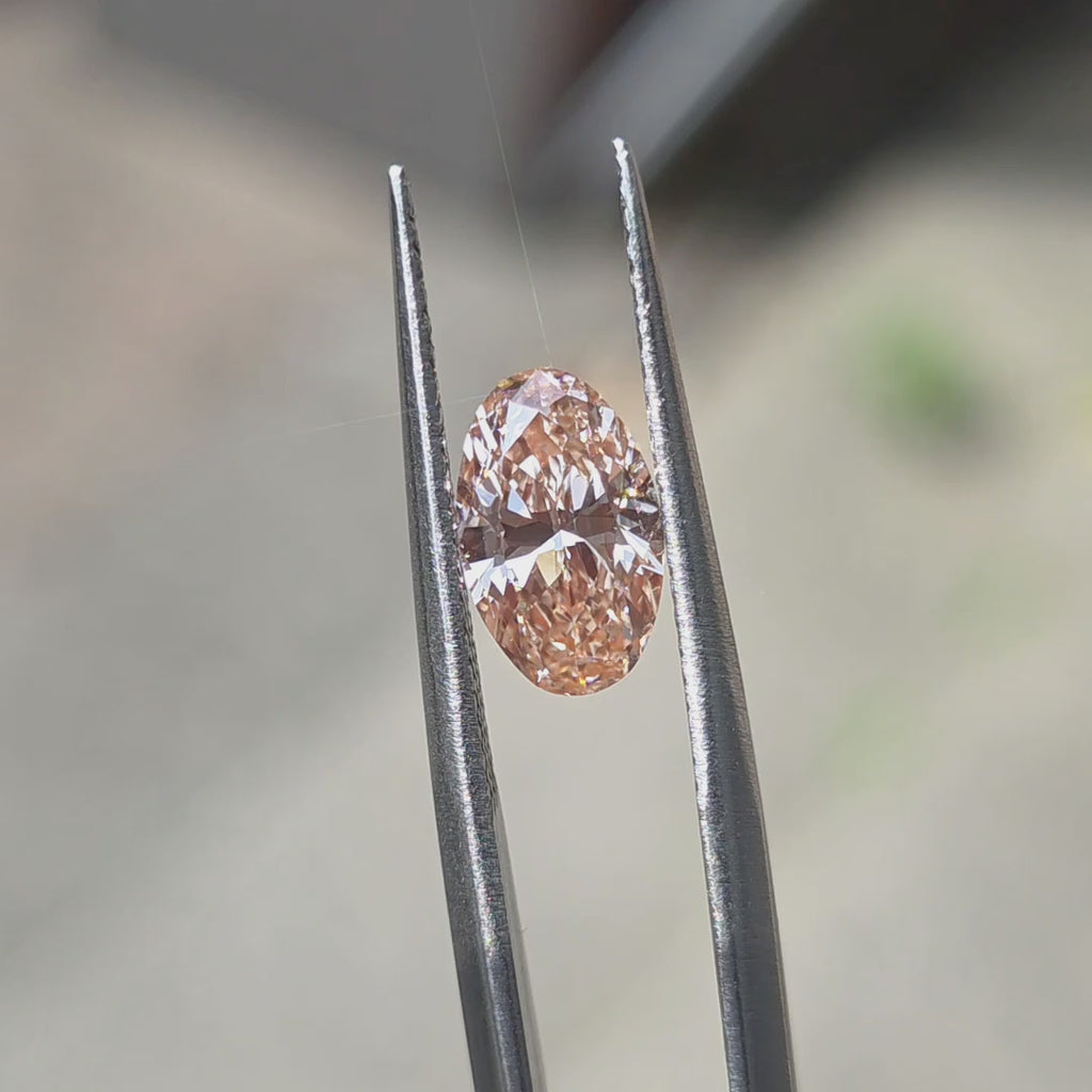 1.56ct oval brilliant cut fancy vivid pink VVS2 lab diamond displaying romantic color in outdoor sunlight.