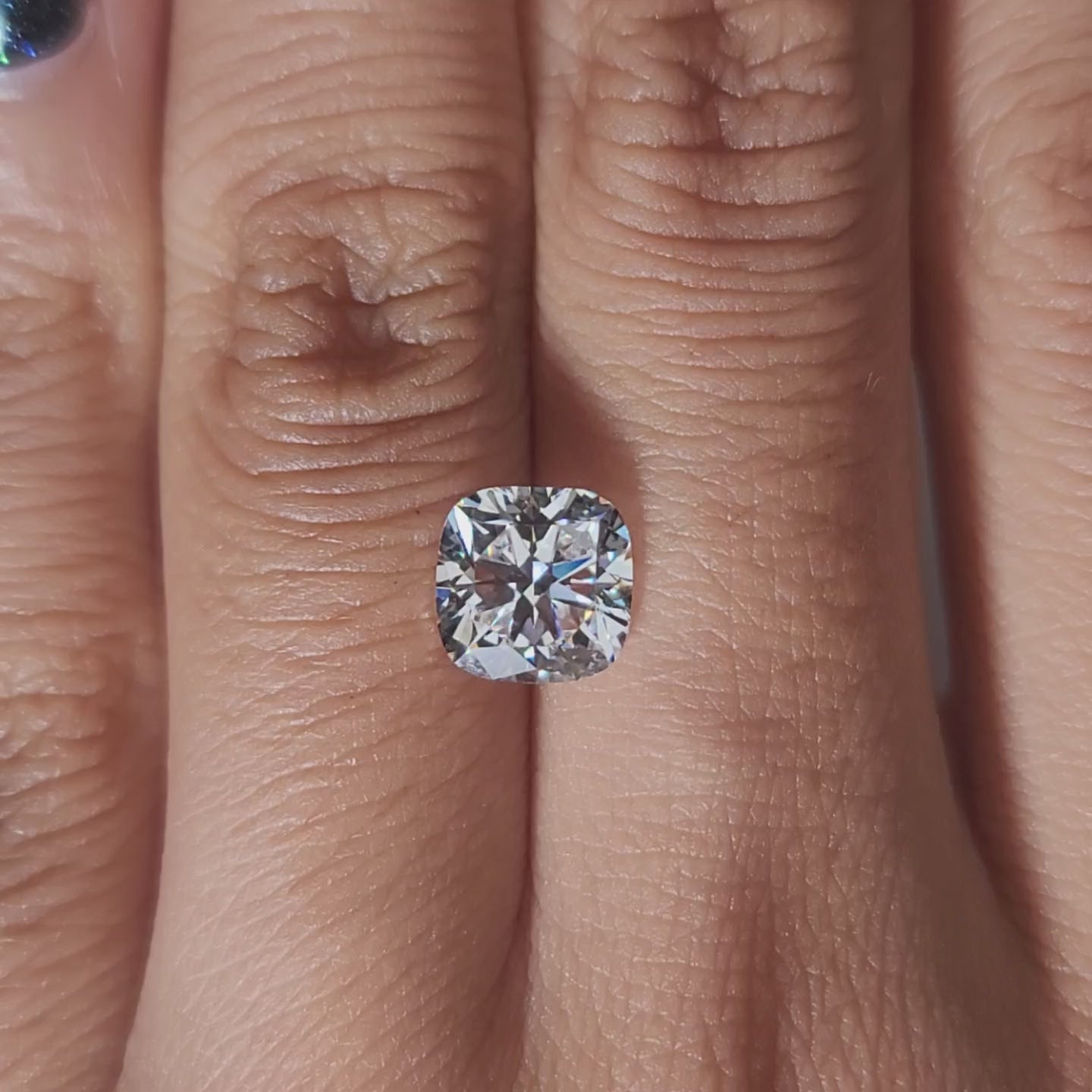 Finger-modeled video of 2.005ct cushion diamond under warm indoor lights