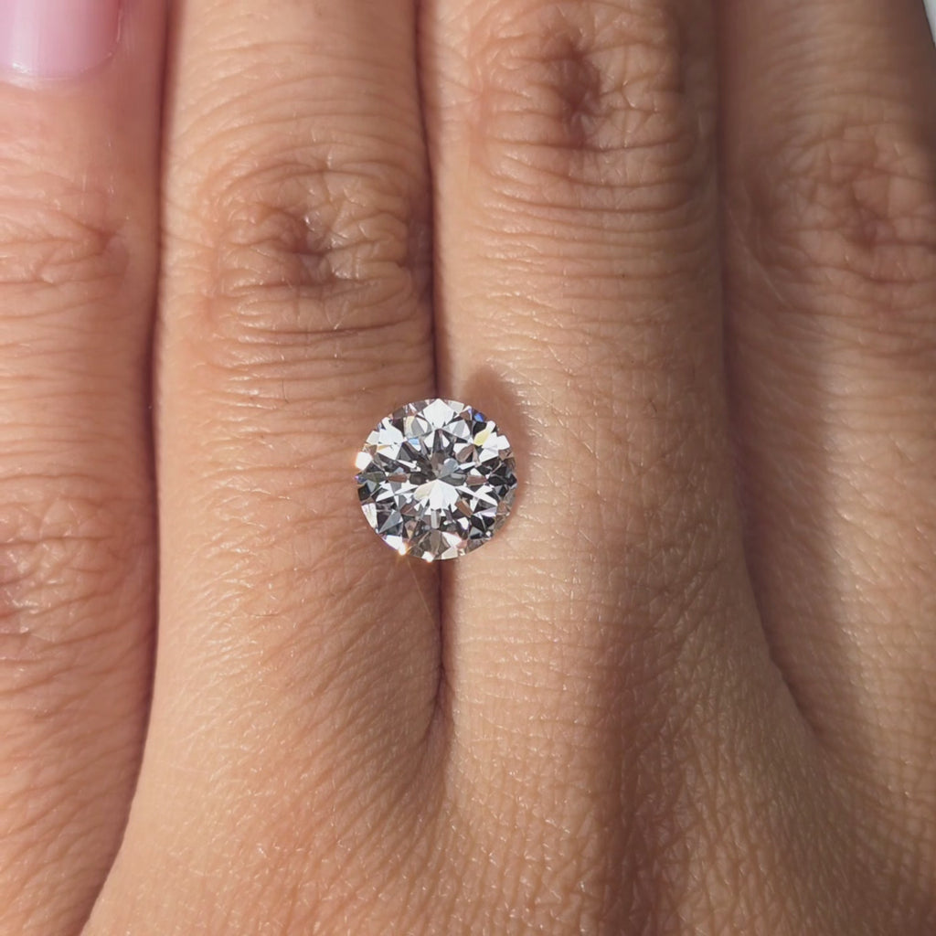 A 2.10ct Crown Arrow Cut™ D color lab diamond held in hand, warm lighting.
