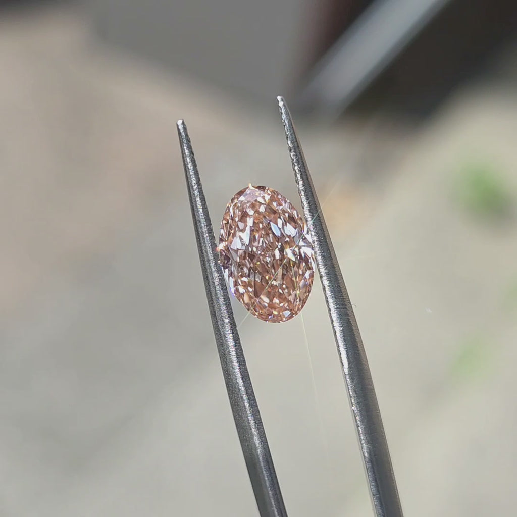 2.07ct oval brilliant cut fancy vivid pink VVS1 lab diamond showing intense pink hue in outdoor sunlight.