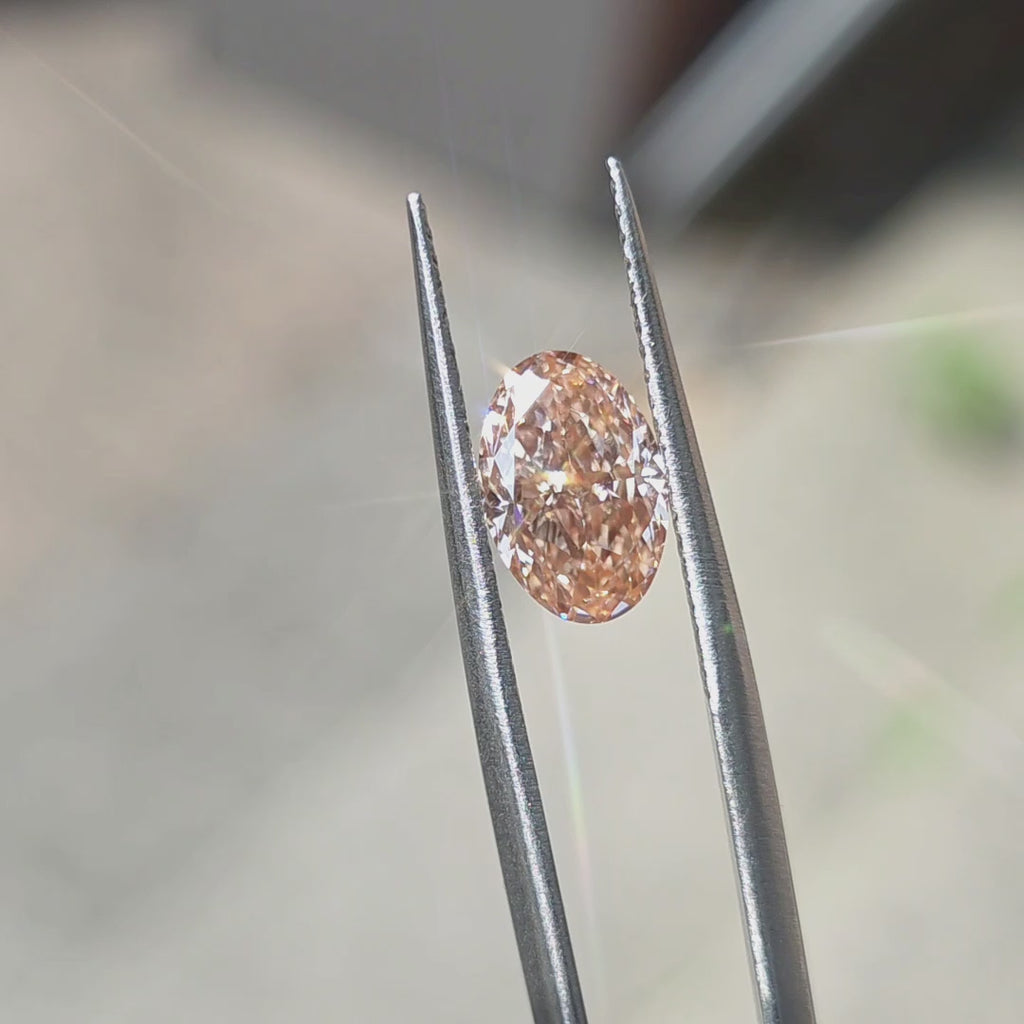 Sunlight reveals the vibrant color of a 2.20ct oval brilliant cut fancy vivid pink lab diamond.