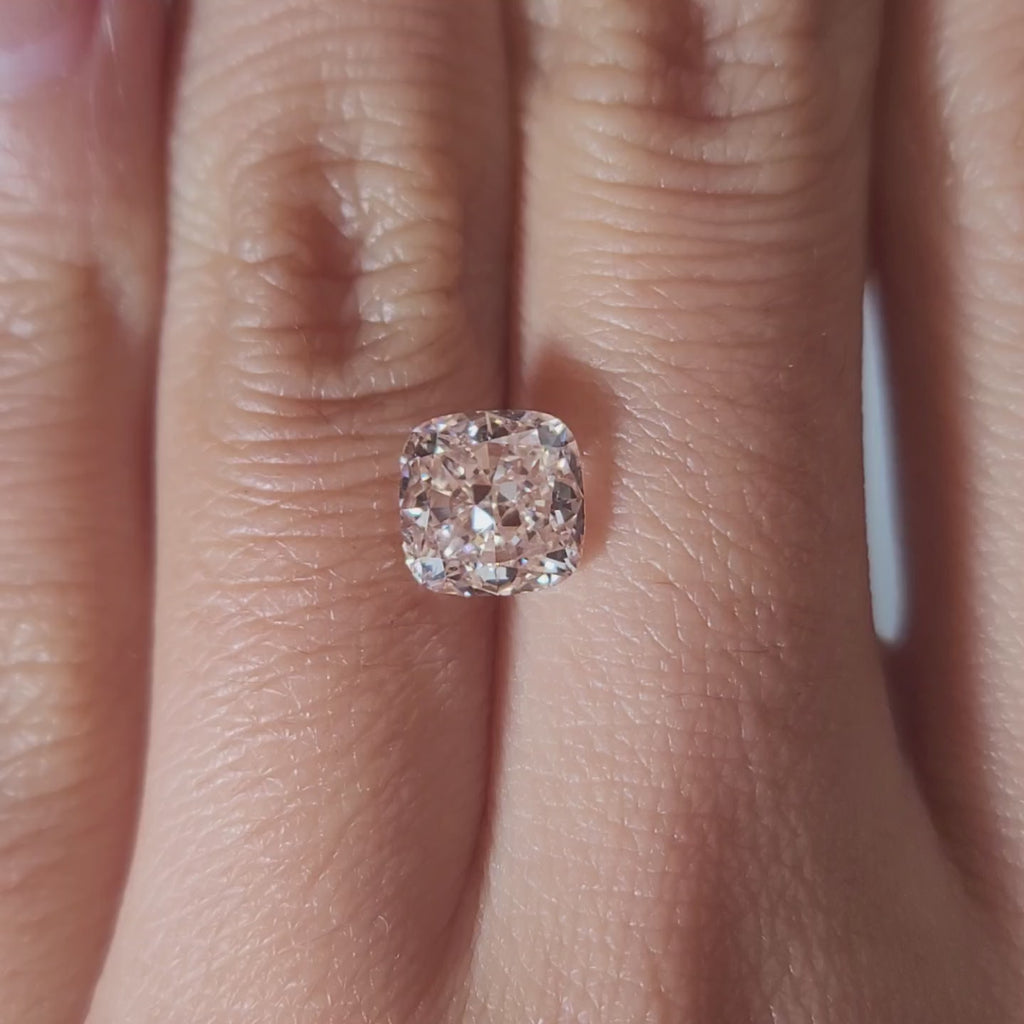 "Hand-modeled video of 2.055ct pink cushion diamond in warm indoor lighting"