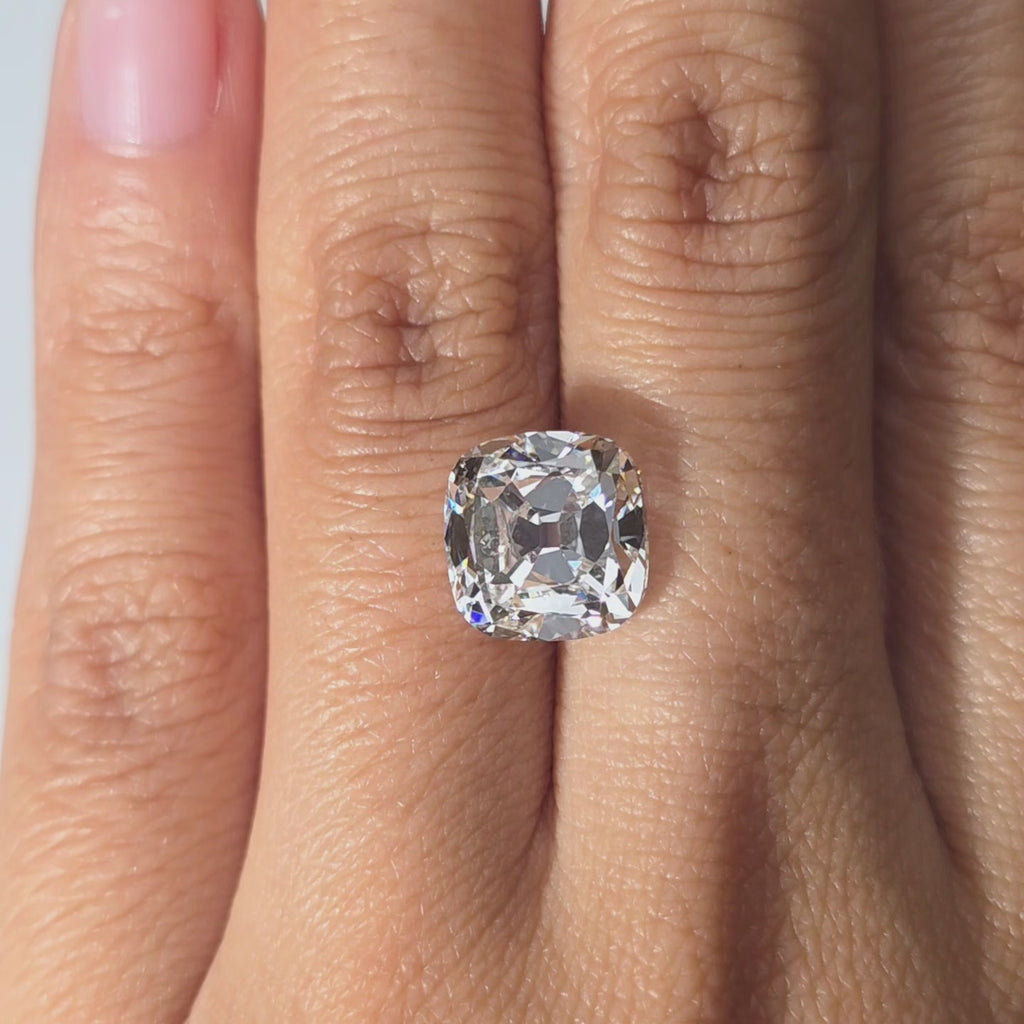 A 5.01ct cushion old mine cut lab diamond displayed in hand under warm indoor light.