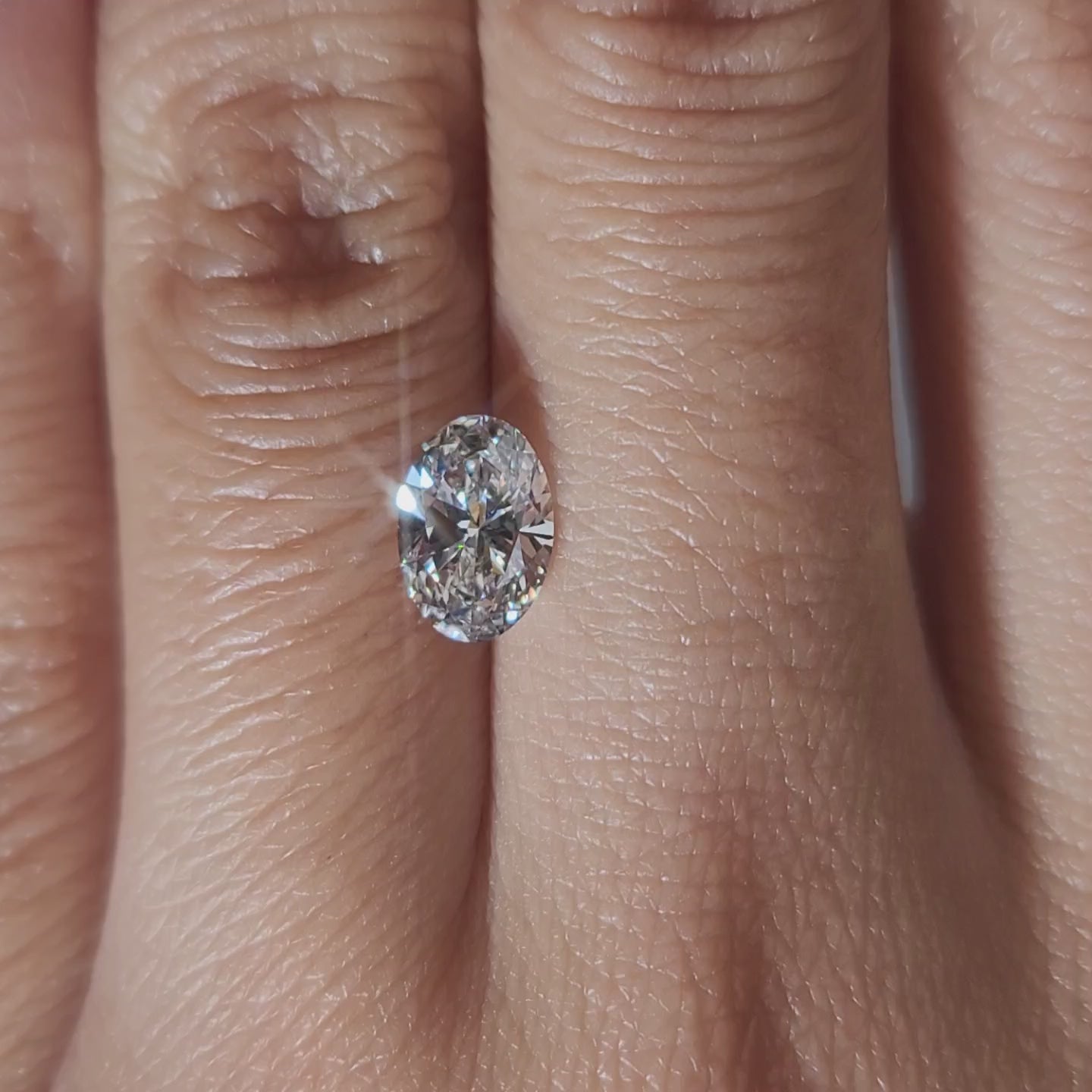 "Hand-modeled video of 1.01ct oval diamond in warm indoor lighting"