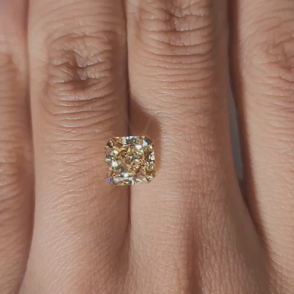 Close-up hand video displaying 2.312ct yellow radiant diamond in cozy indoor light