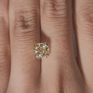 Close-up hand video displaying 2.312ct yellow radiant diamond in cozy indoor light