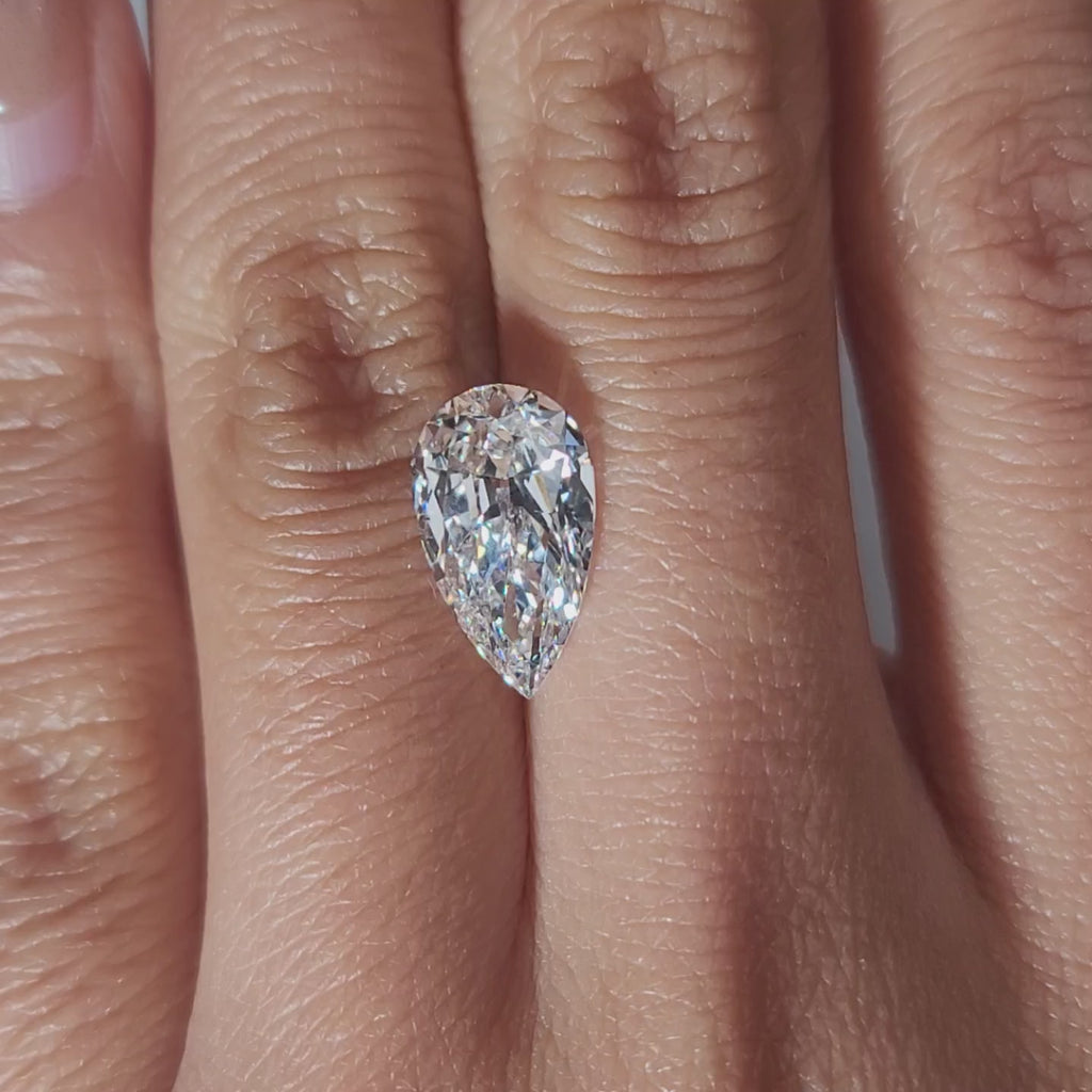 "Hand-modeled video of 3.033ct pear diamond in warm indoor lighting"