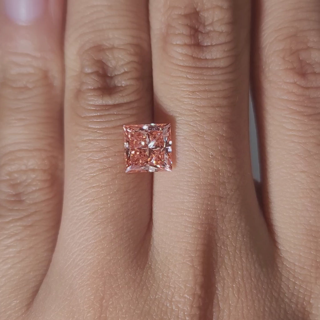 Hand-modeled video of 2.41ct vivid pink princess diamond under warm lighting