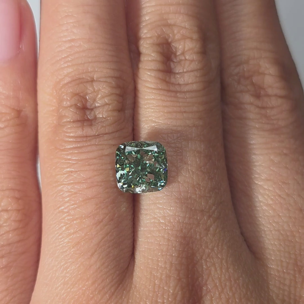 Hand showcasing a 3.00ct cushion cut fancy vivid green VS1 lab diamond in warm indoor light.