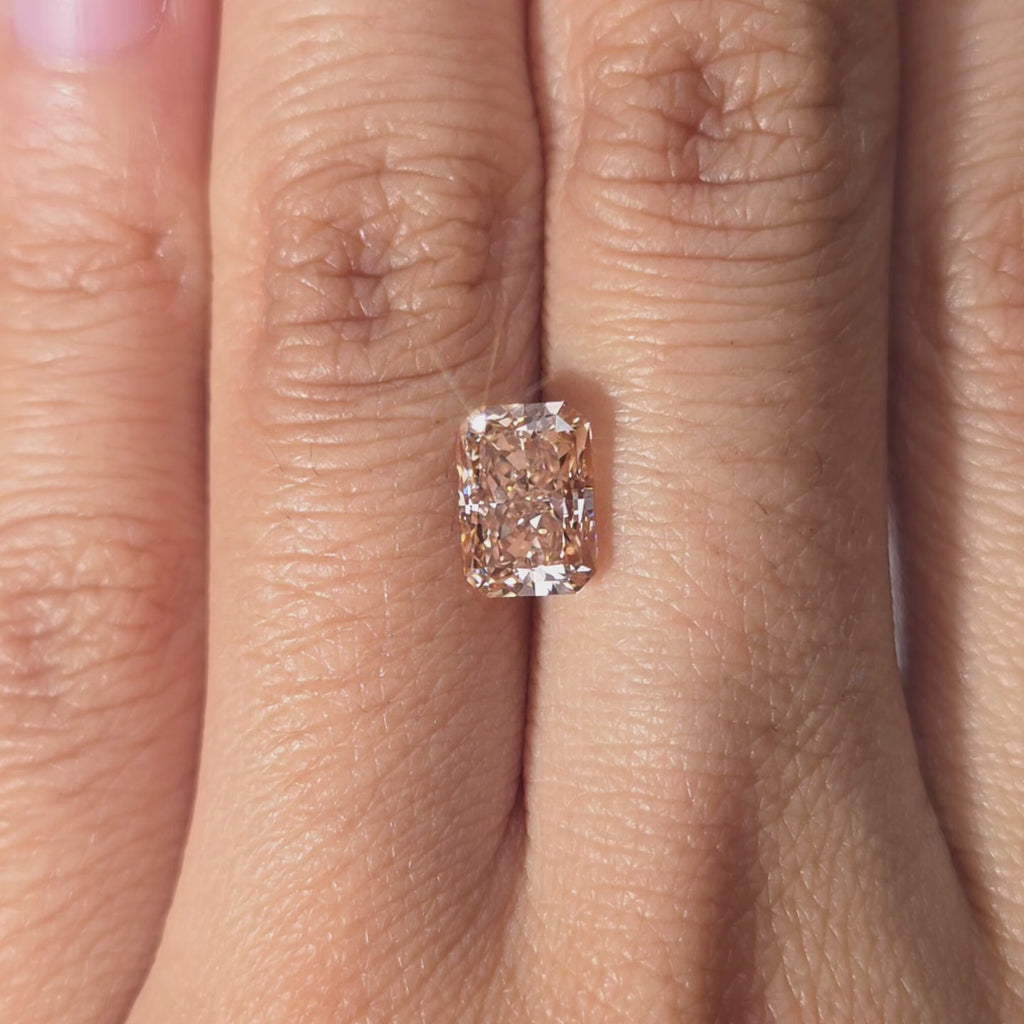 Hand modeling a 2.08ct radiant cut fancy vivid pink lab diamond in warm indoor light.