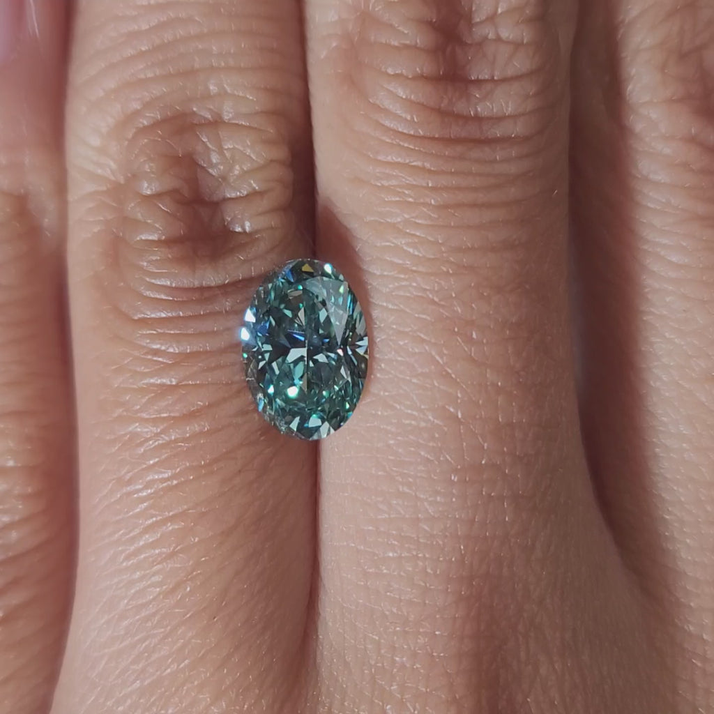 "Hand-modeled video of 2.086ct bluish green oval diamond in warm indoor lighting"