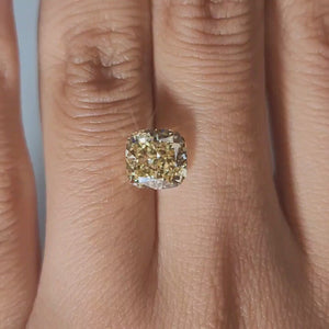 Hand-display video showing 2.720ct yellow cushion diamond in warm interior light